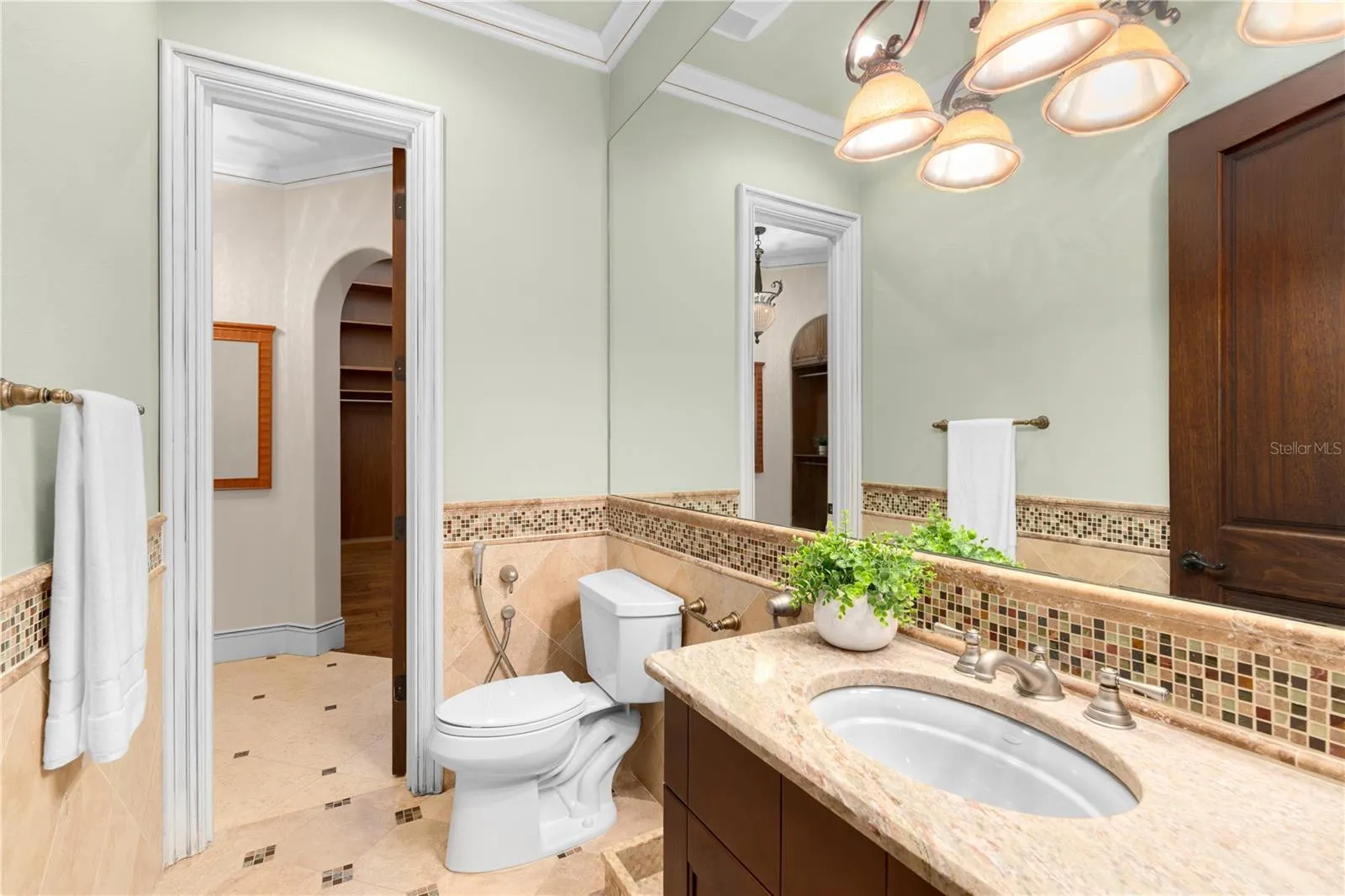 A beautifully appointed powder bath pairs custom wood cabinetry with natural stone surfaces and refined tile detailing.