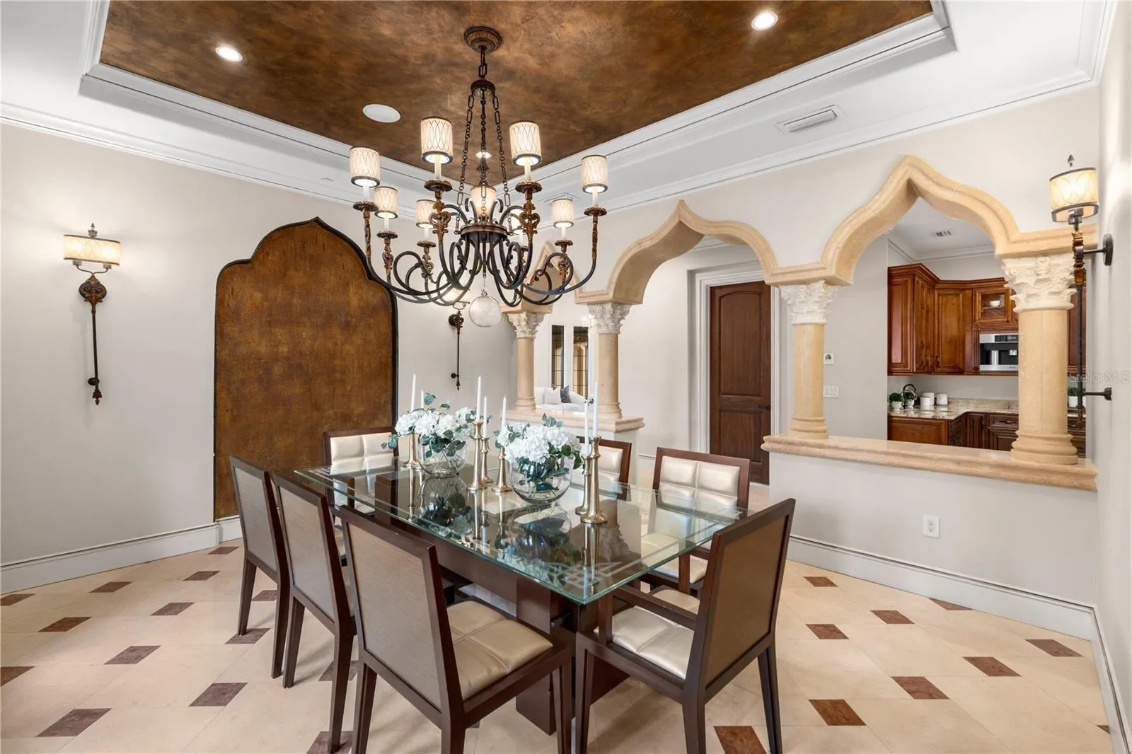 Graceful arches and a statement chandelier frame the formal dining room, showcasing this Lake Mary estate's timeless architectural character and attention to detail.