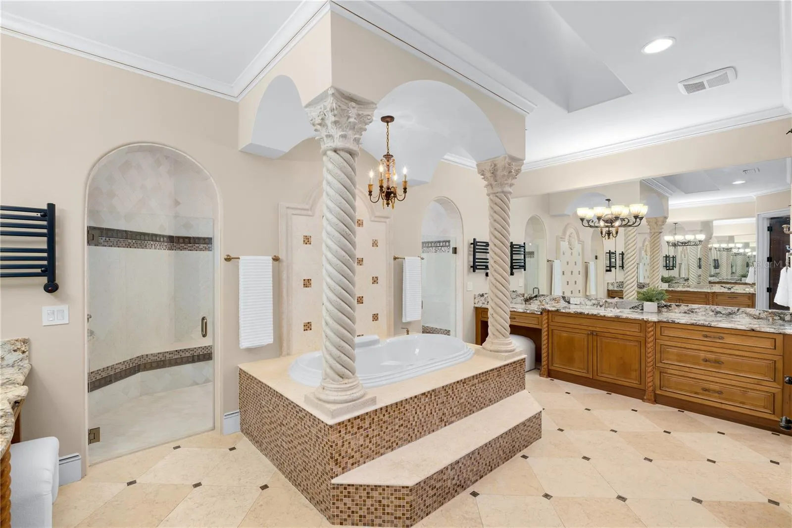 The spa-inspired primary bath makes a dramatic statement with an elevated Jacuzzi soaking tub, sculptural columns, extensive cabinetry and dual vanity areas.
