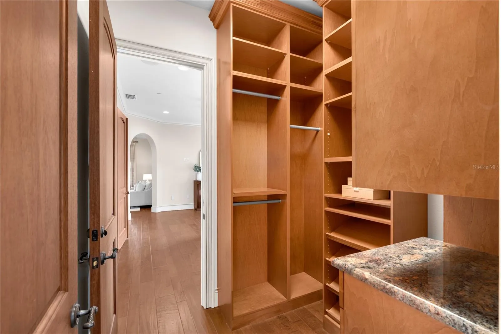 A custom walk-in wardrobe offers thoughtfully designed built-in shelving, hanging areas and stone-topped cabinetry.
