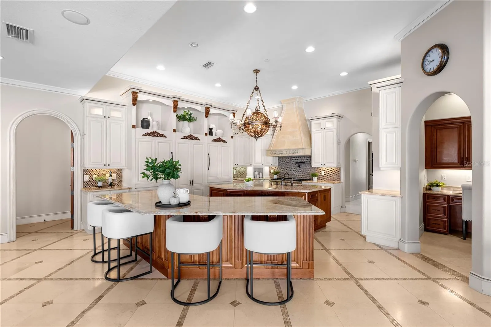 The chef's kitchen is anchored by an oversized island with seating and custom cabinetry, seamlessly connected to this Lake Mary estate's principal living spaces.