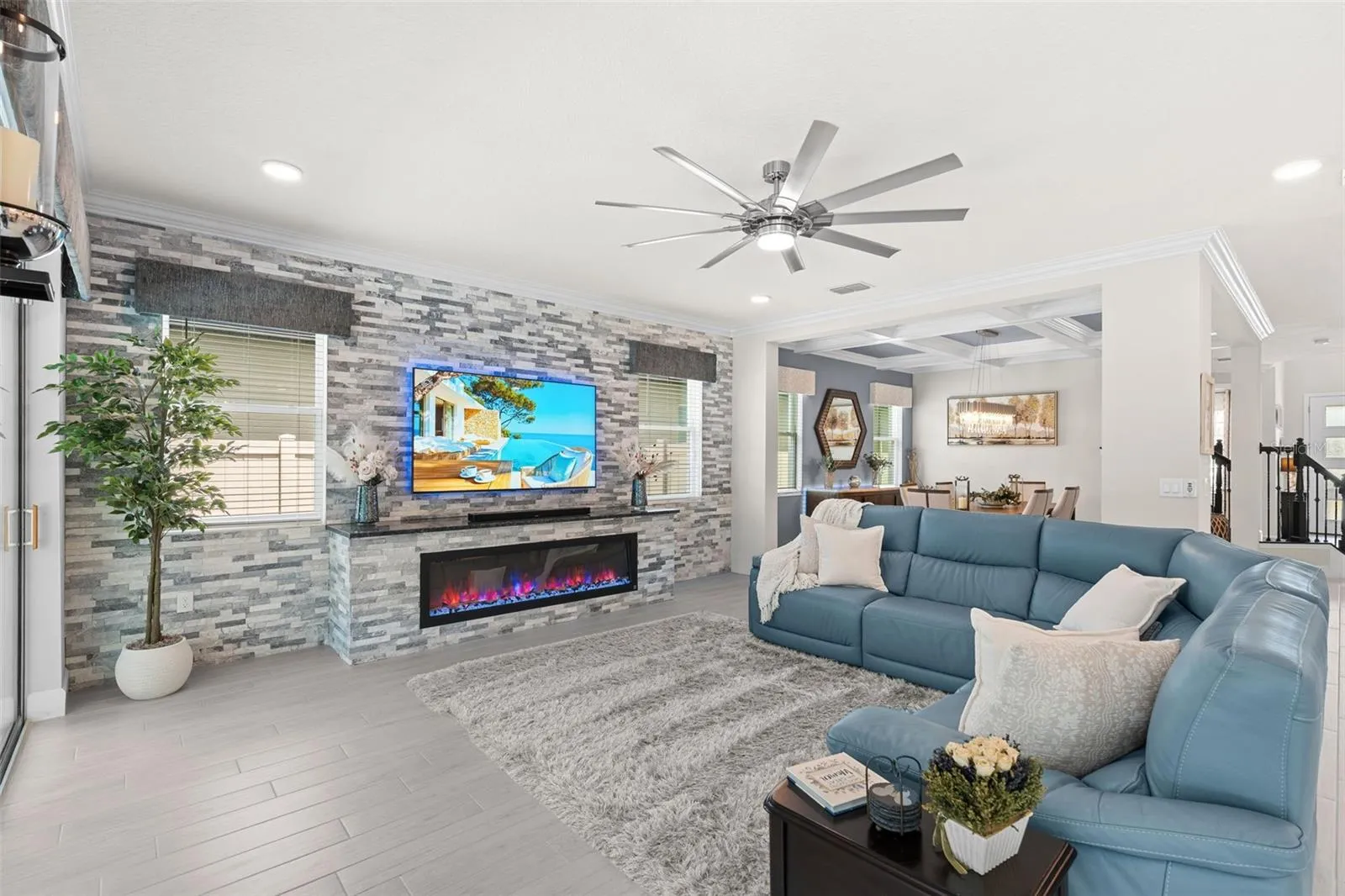 Spacious open living room with a stacked stone feature wall that includes an electric fireplace.