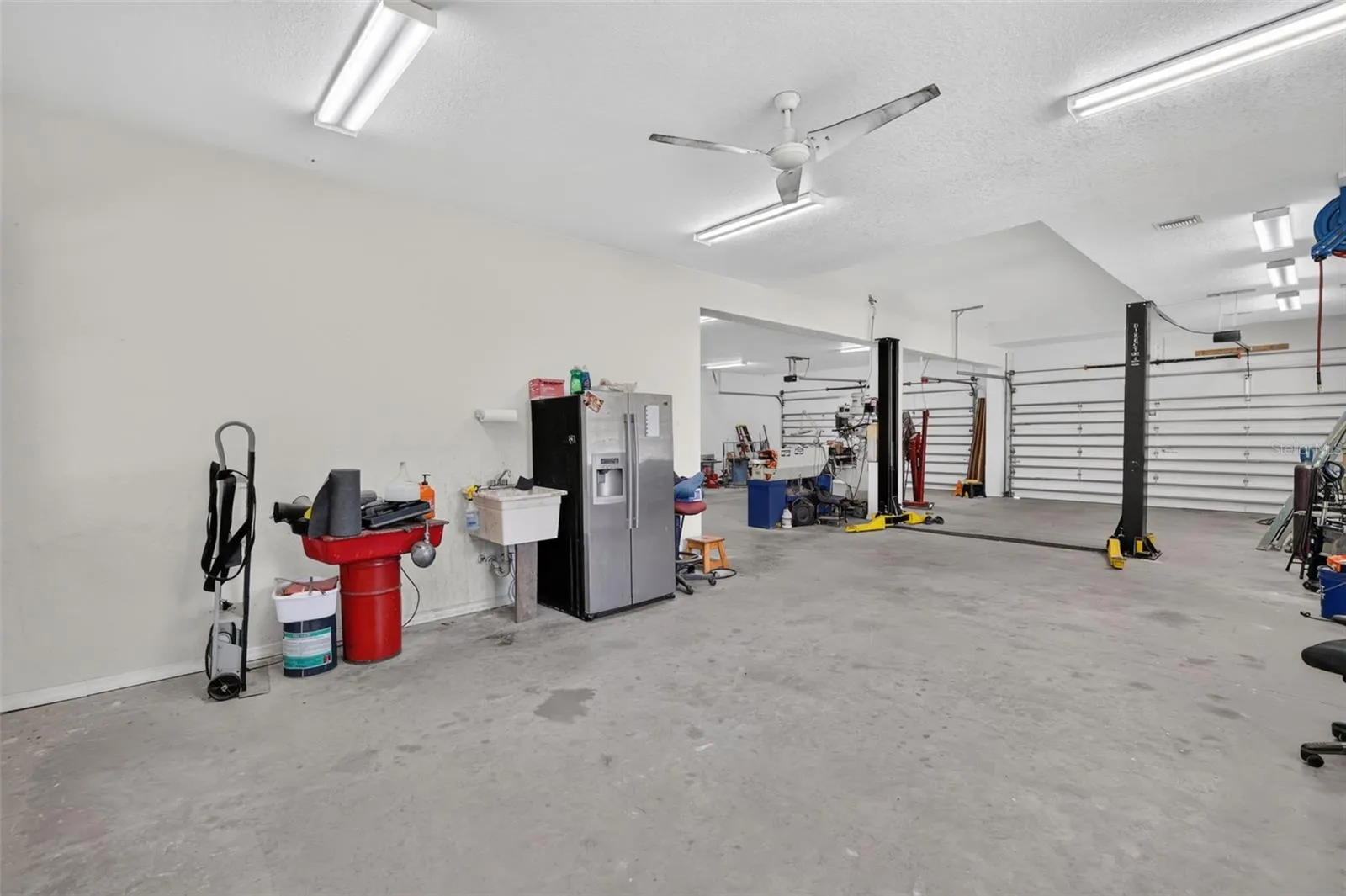Multiple garage doors, a utility sink, industrial fans, and abundant electrical service make this workshop a dream for any trade or hobby.