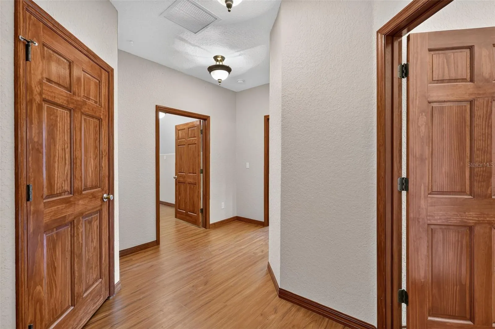 Upstairs, a well-appointed hallway with hardwood flooring leads to additional bedrooms, a full bath, and storage.