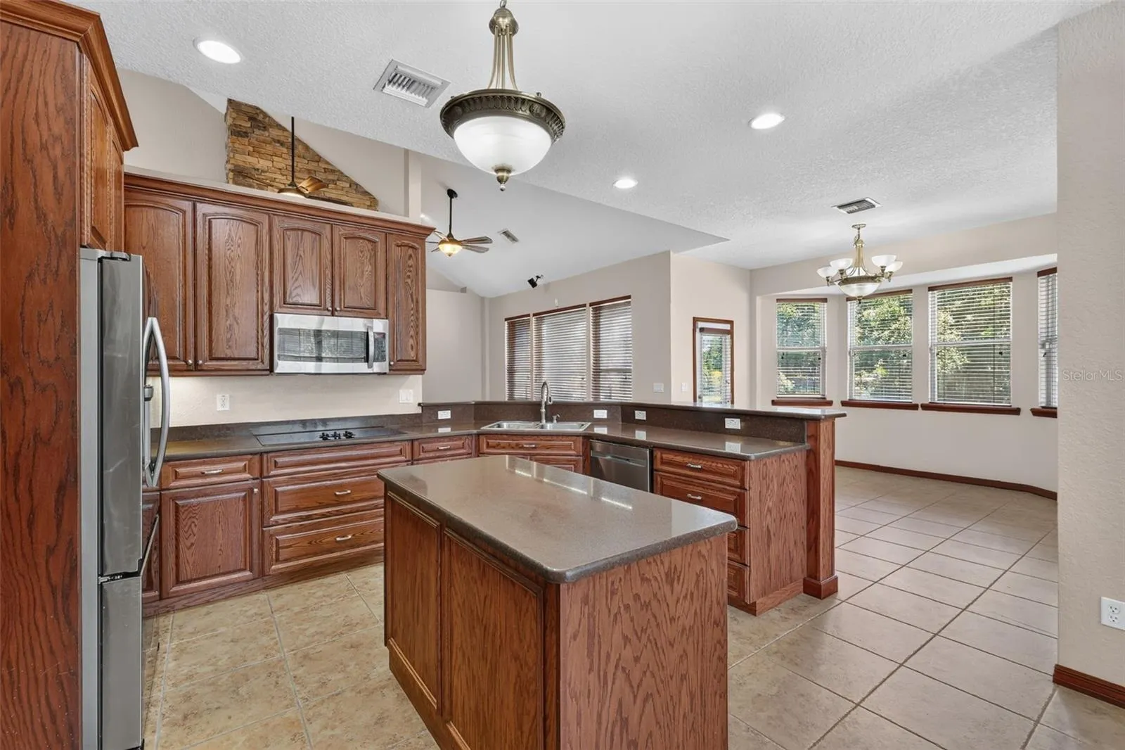 The chef's kitchen features a center island, abundant oak cabinetry, stainless steel appliances, and flows directly into a sunny breakfast nook.