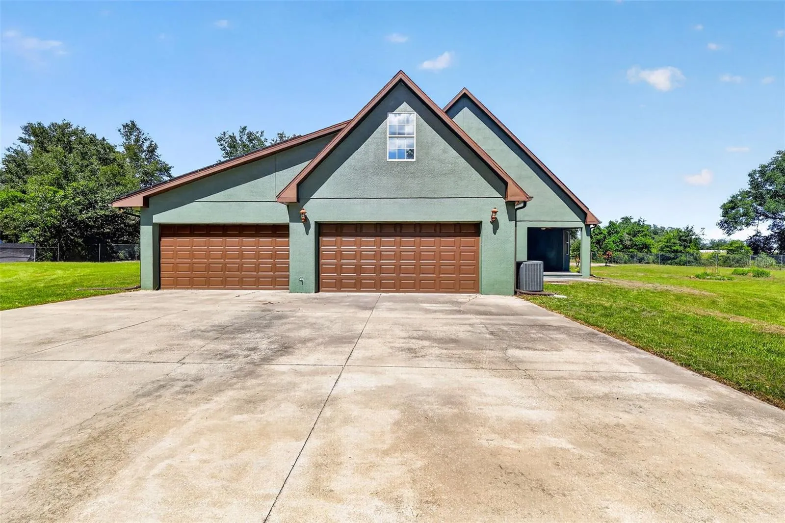 The 4+ car workshop matches the home's architectural style with a wide concrete drive, coach lanterns, and its own dedicated AC system.