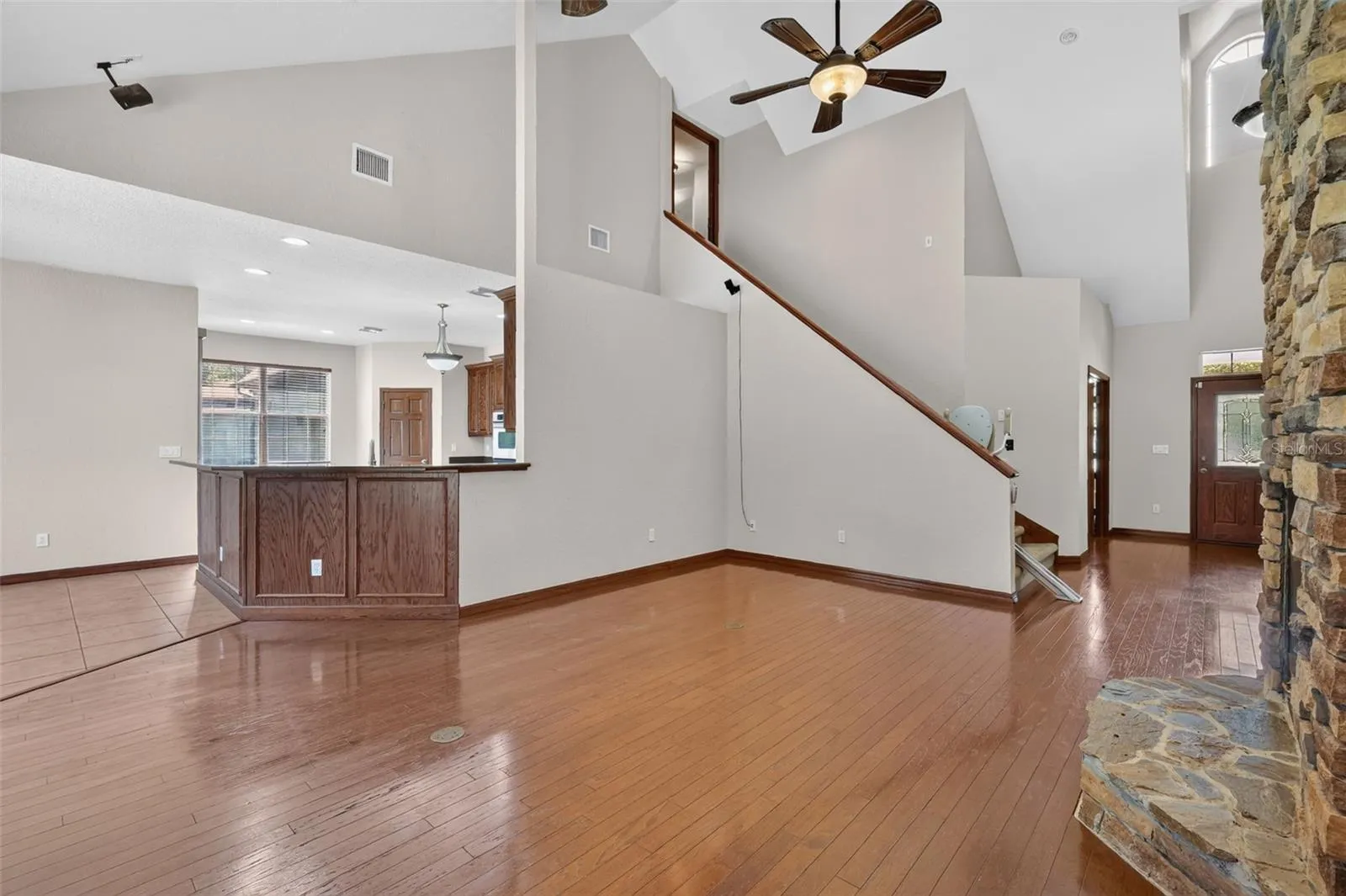Step inside to dramatic vaulted ceilings, rich hardwood floors, and a stunning floor-to-ceiling stacked stone fireplace that anchors the entire living space.