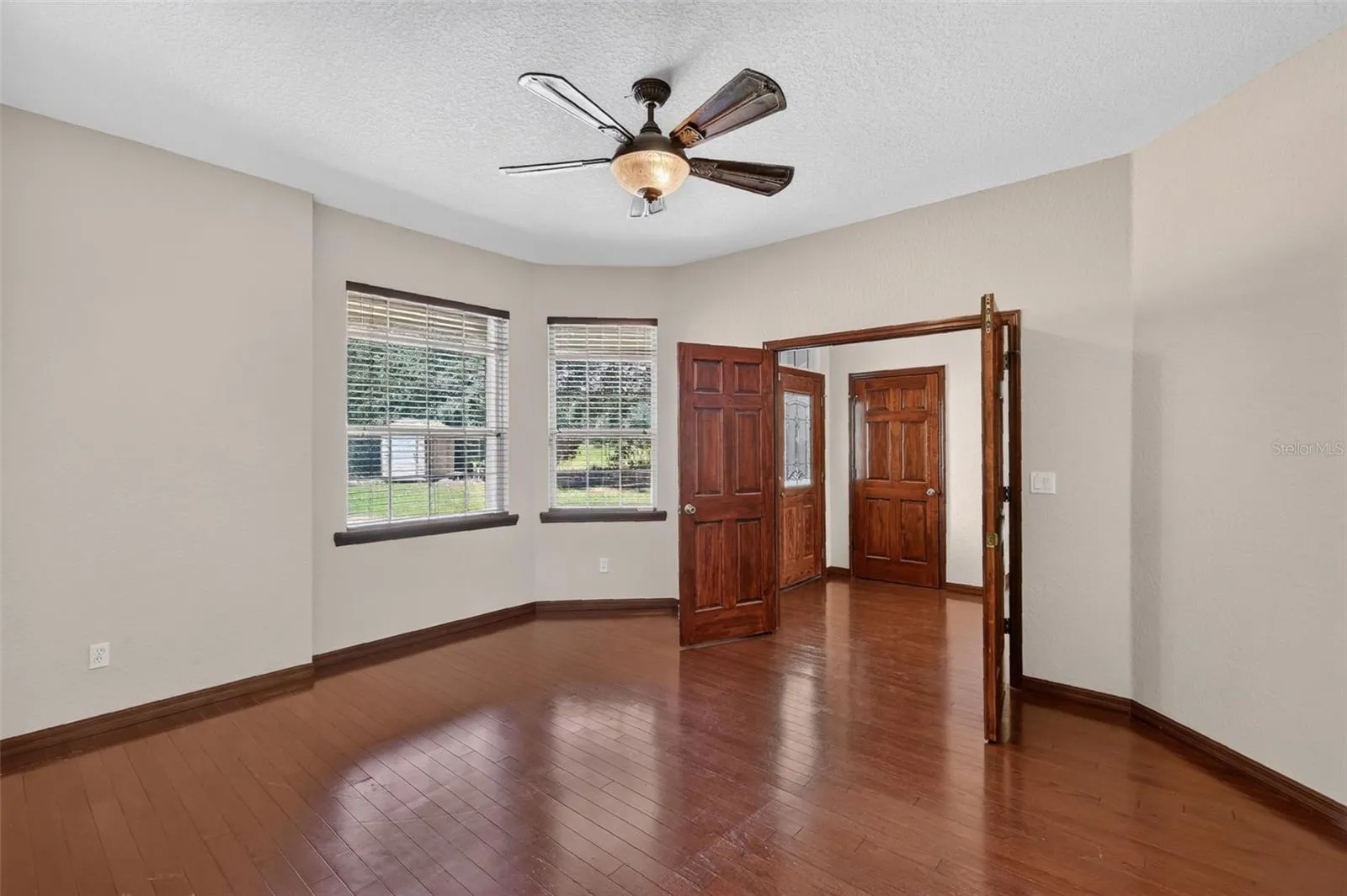 A dedicated formal living room or home office features elegant double doors, hardwood floors, and peaceful views of the property.