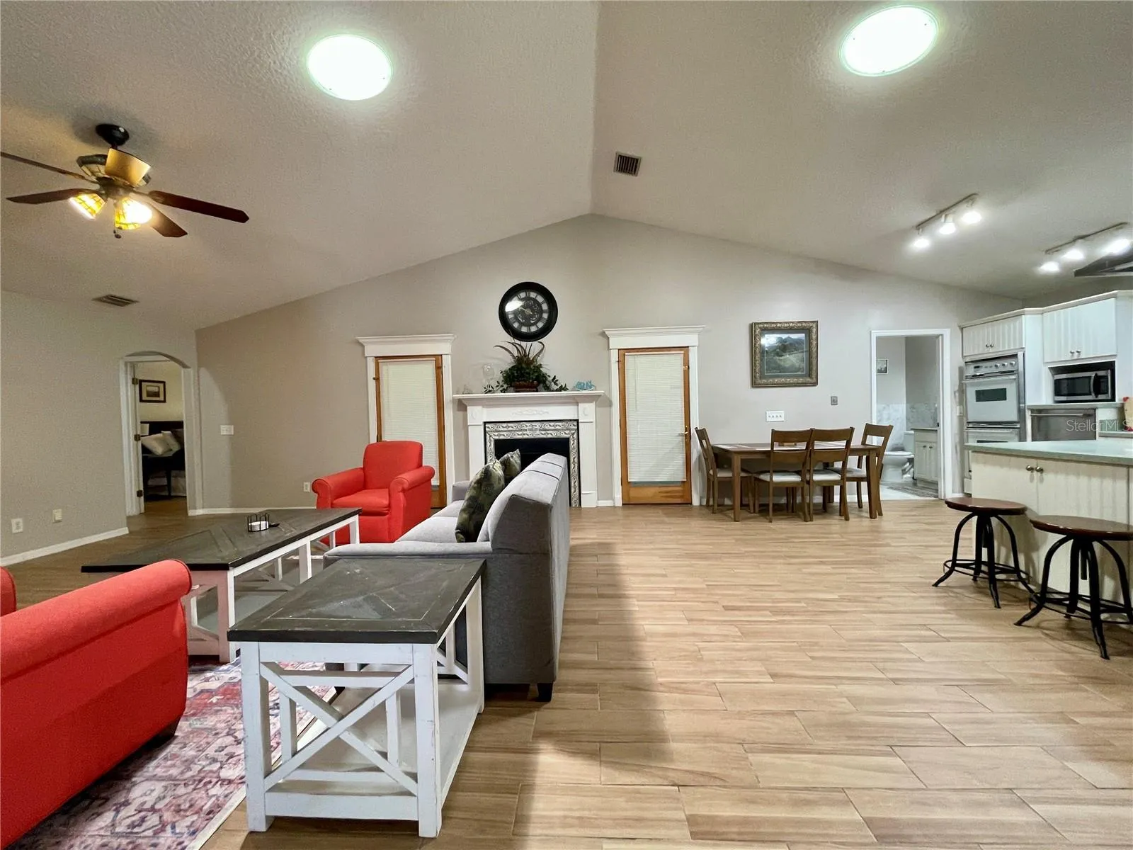 Spacious open-concept living, dining, and kitchen areas are unified beneath a vaulted ceiling, with a fireplace providing an inviting focal point.