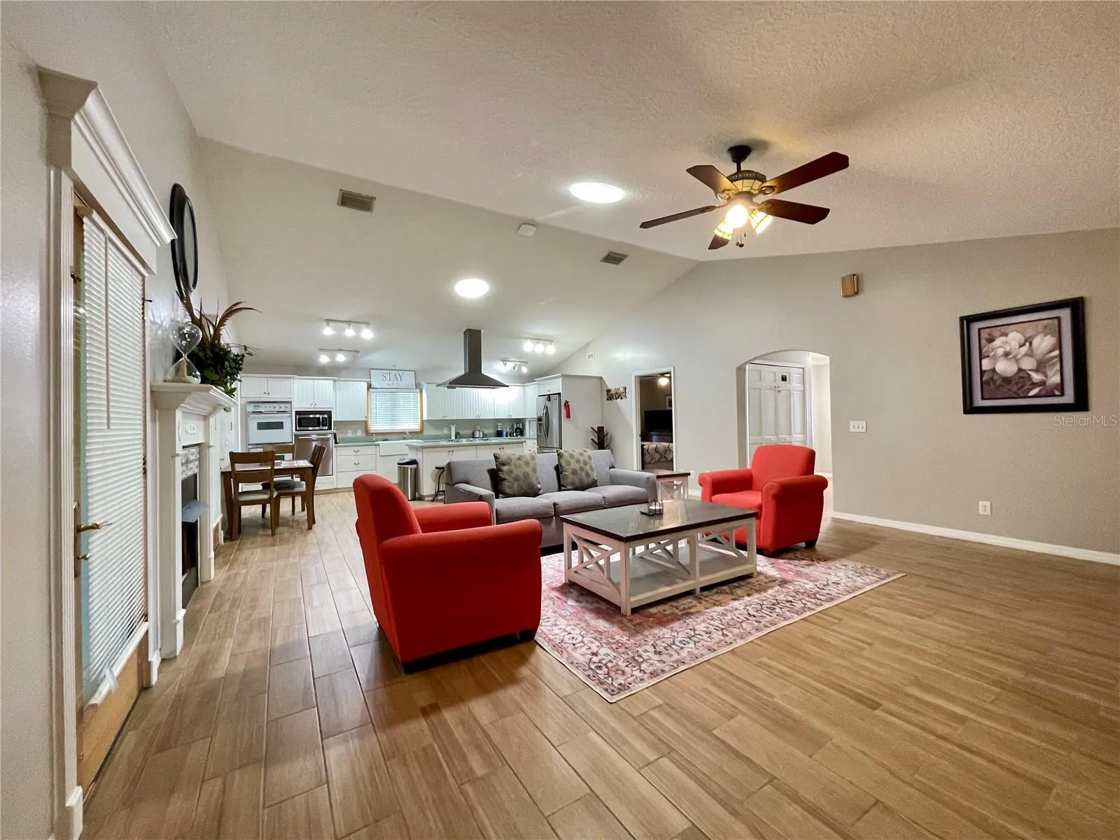 A broad view showcases the spacious main living area and its seamless connection to the kitchen, with skylights offering an abundance of natural light and plenty of room for multiple seating arrangements.