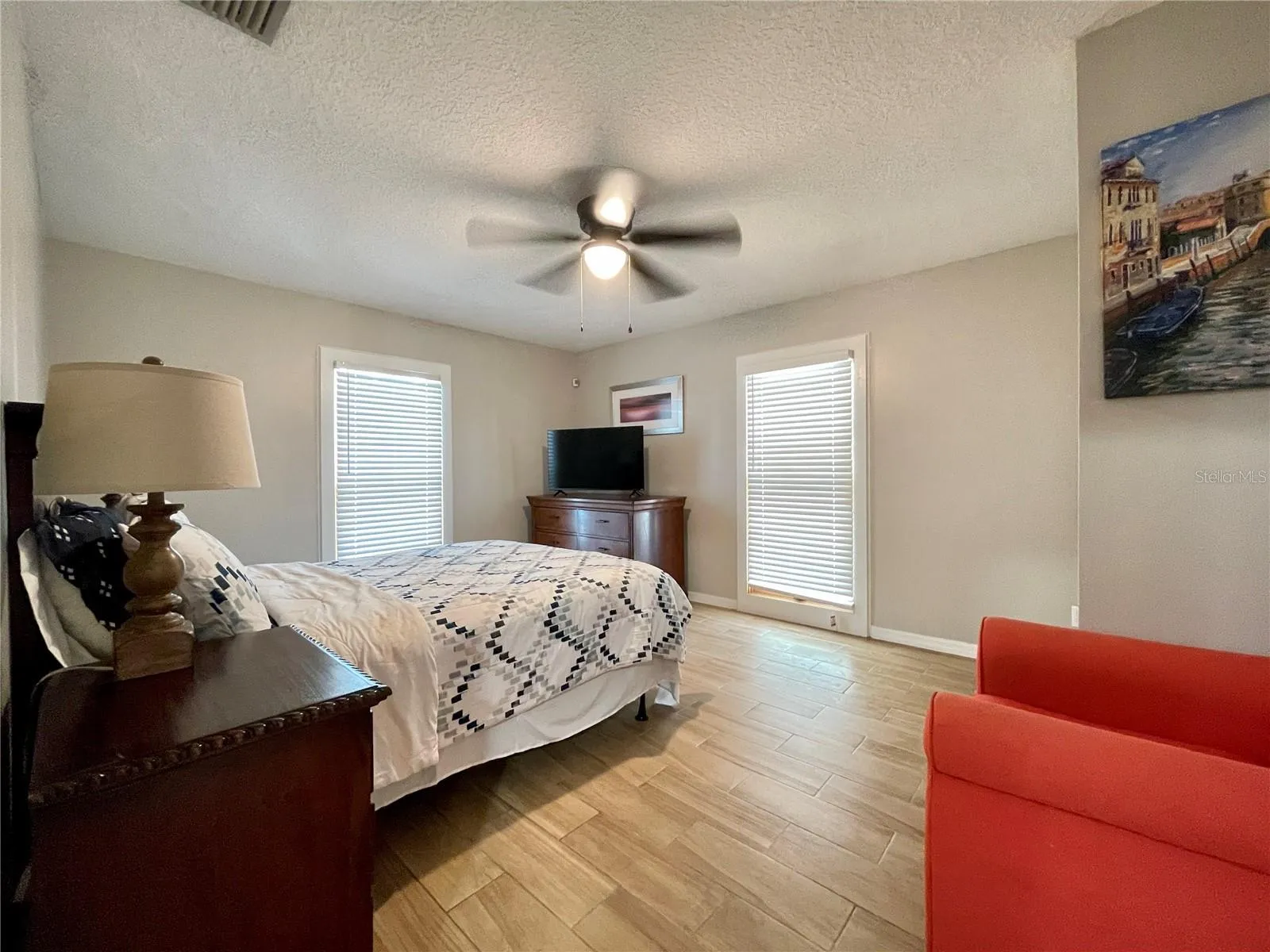 Spacious bedroom features neutral finishes, a ceiling fan, and multiple windows that bring natural light into the room.