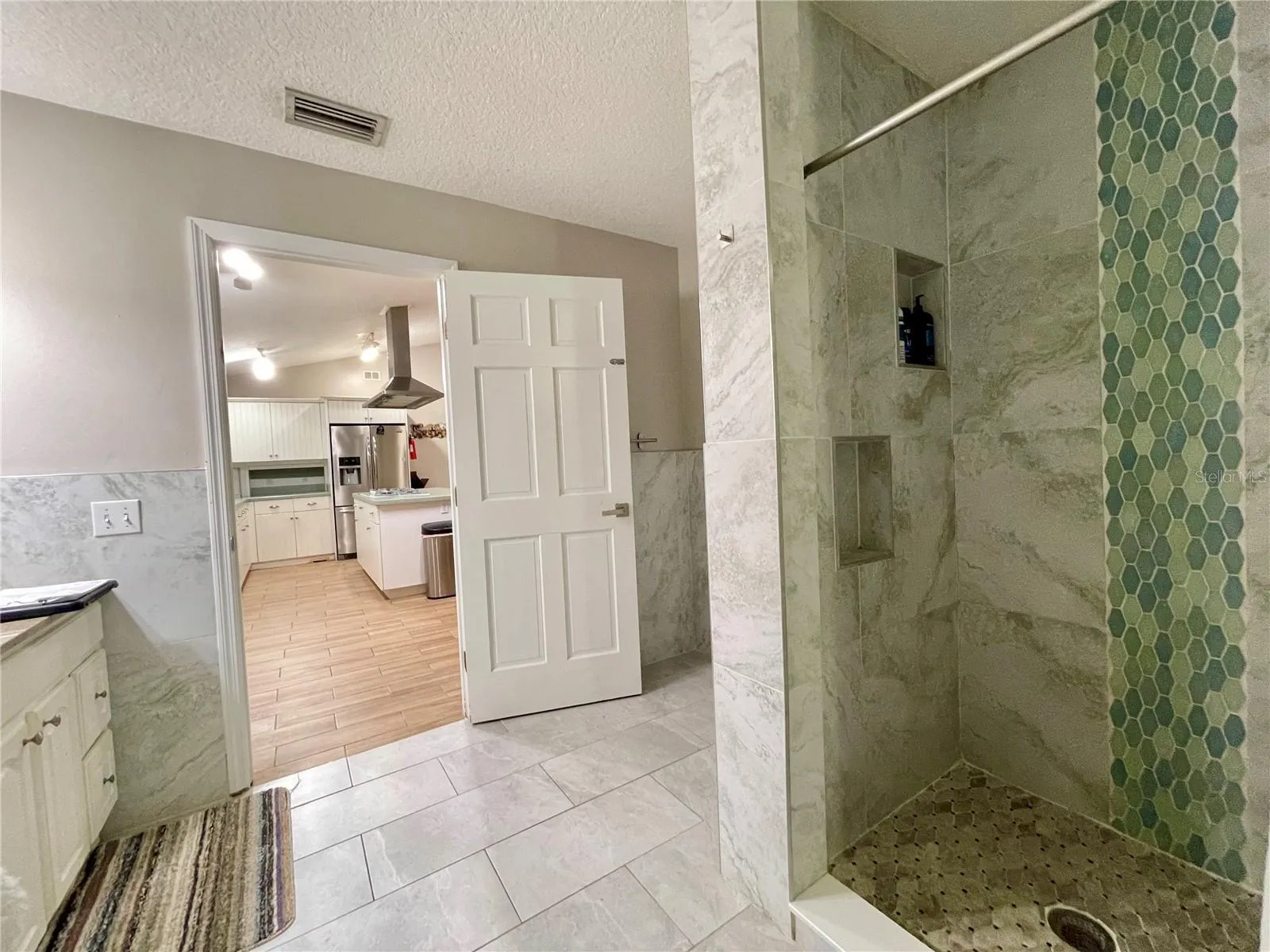 Tiled walk-in shower features built-in niches and a decorative mosaic accent for a polished, contemporary look.