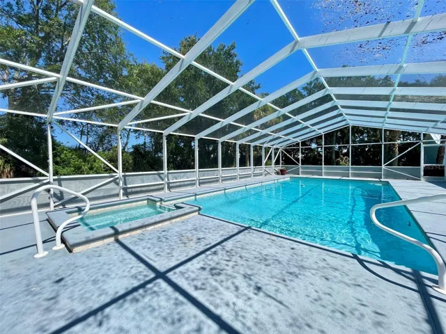 Expansive screened pool area and adjoining spa, with generous deck space for outdoor seating and recreation.