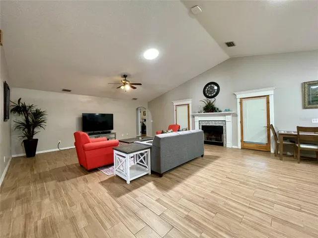 The expansive living area offers flexible furniture placement, a vaulted ceiling, fireplace, and convenient connection to the adjacent dining space.