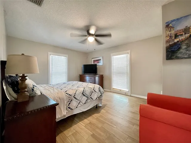 Spacious bedroom features neutral finishes, a ceiling fan, and multiple windows that bring natural light into the room.