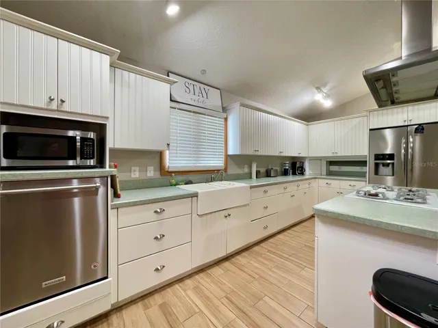 A closer view highlights the generous cabinet storage, farmhouse-style sink, stainless steel appliances, and long stretches of countertop for everyday meal preparation.