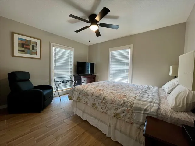 Bright bedroom offers two tall windows, neutral finishes, and a ceiling fan, with ample space for additional furnishings.