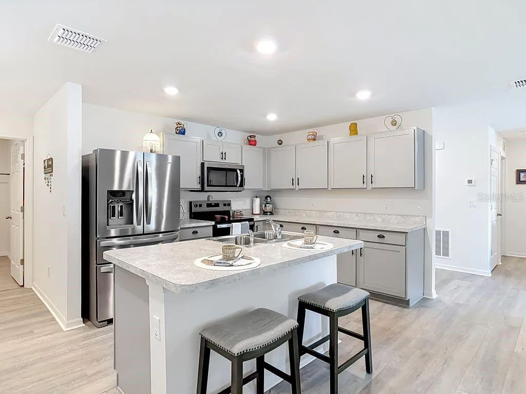 Kitchen: luxury vinyl flooring, breakfast bar with sink and dishwasher, stainless steel appliances. Recessed lighting. Open to Dining room and family room
