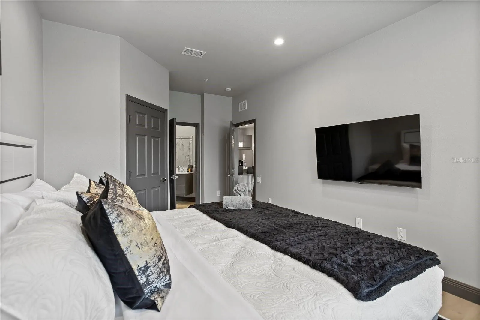 Primary bedroom with wall-mounted TV and access to the en-suite bathroom