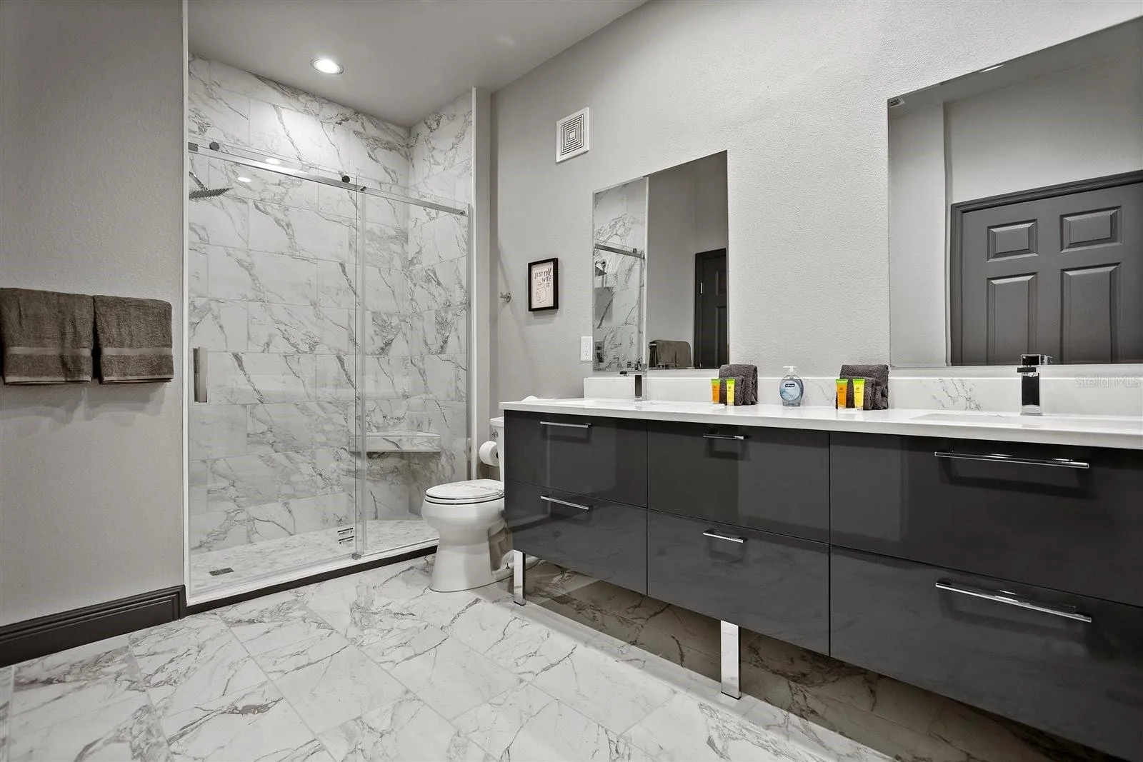 Beautifully renovated second bathroom with dual floating vanity and quartz countertops