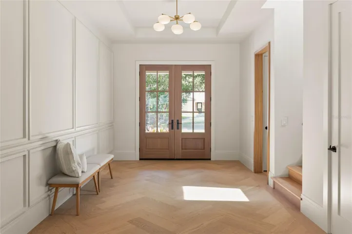 Welcoming foyer features custom herringbone-pattern white oak flooring, a tailored accent wall and white oak-cased openings