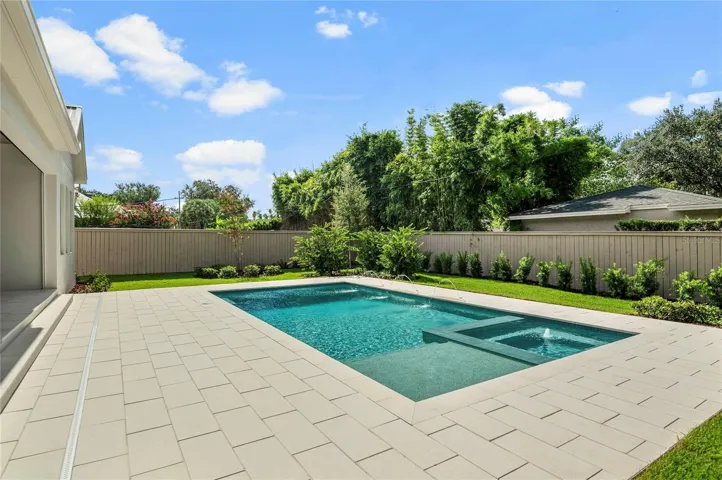 Artistic Paver decking surrounded by meticulously landscaped backyard with custom fencing