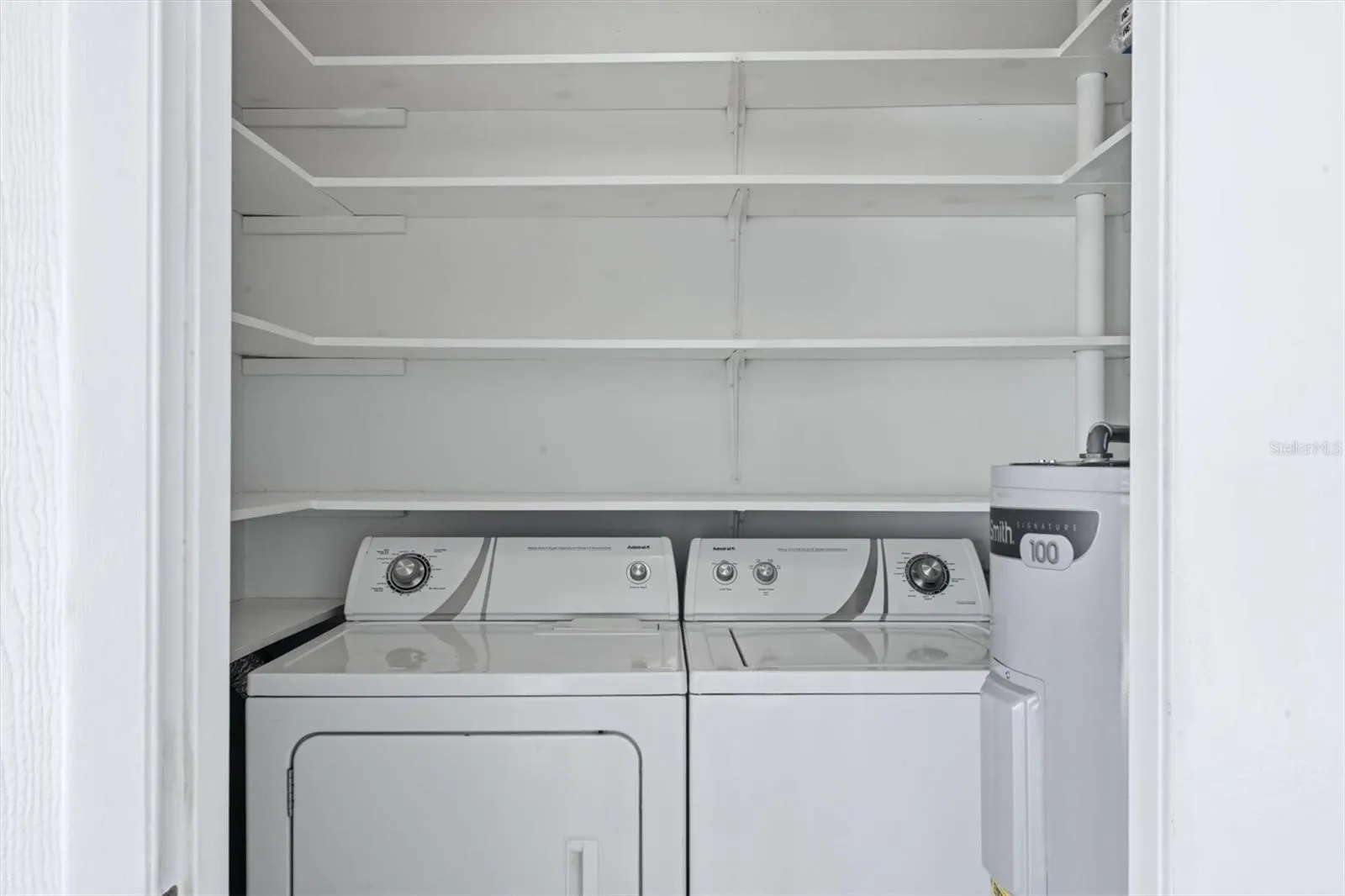 Air conditioned laundry room / storage room is located next to kitchen door with floor to ceiling shelving and water heater