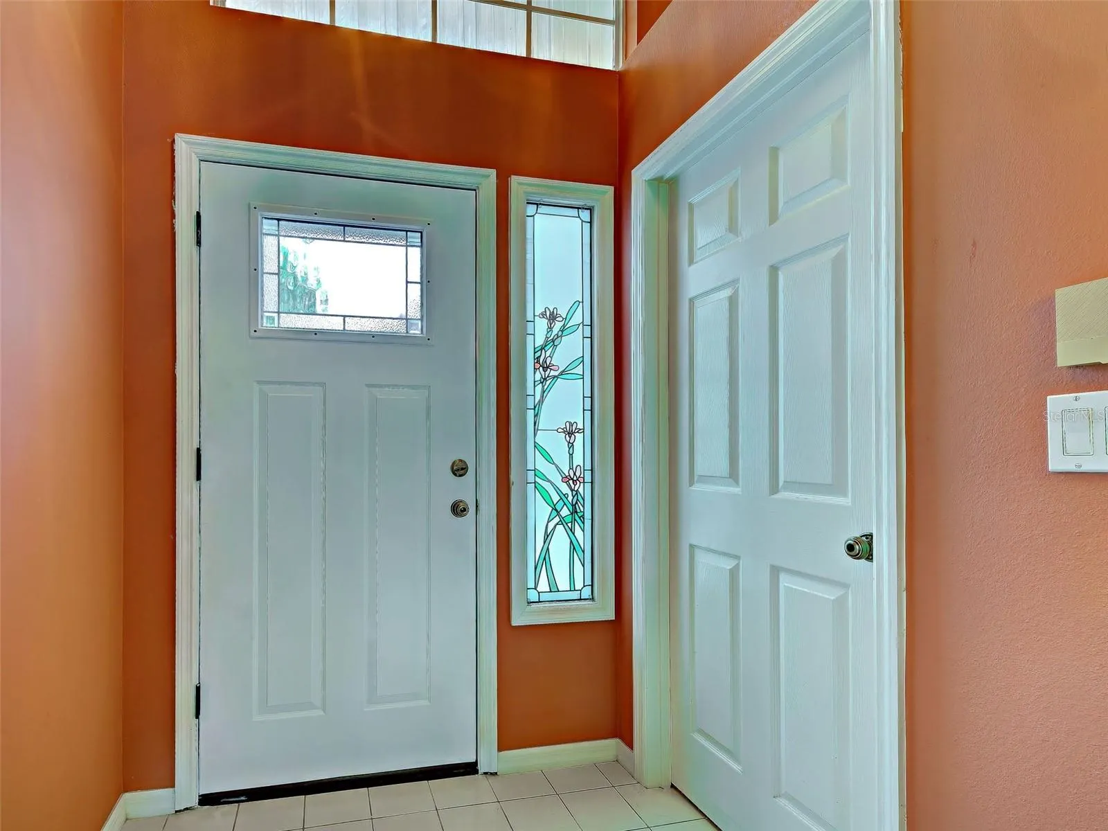 Standing in the entryway looking back at the new door and stained glass side panel. The laundry room is to the right.