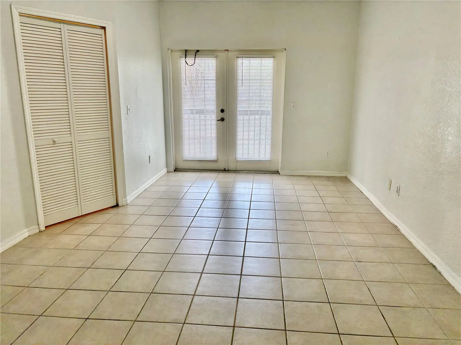Primary suite with French doors opening to small balcony.  Walk-in closet at left.