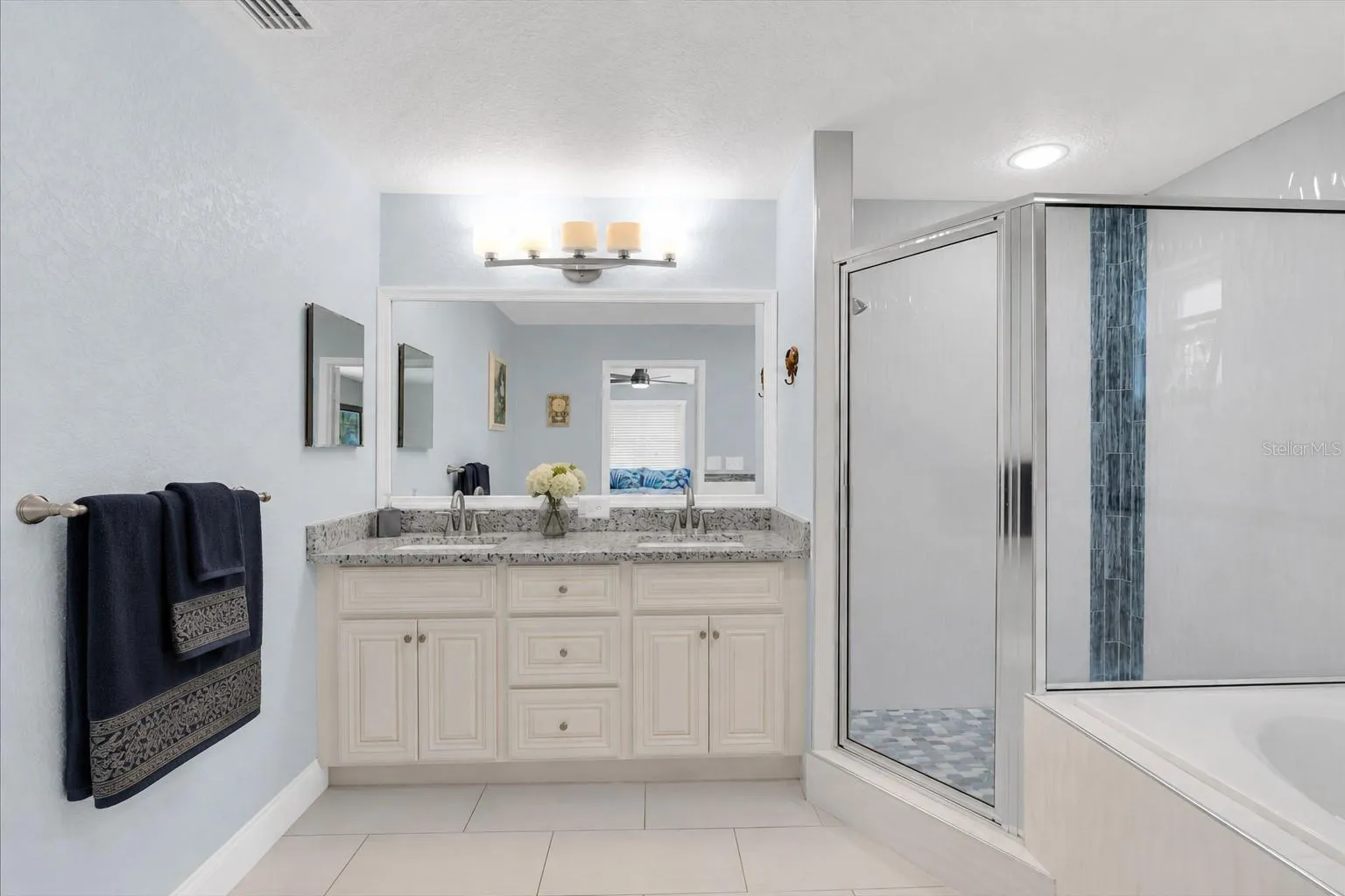 The primary bathroom is spacious with double sinks, a glass shower enclosure and a jetted, deep tub.