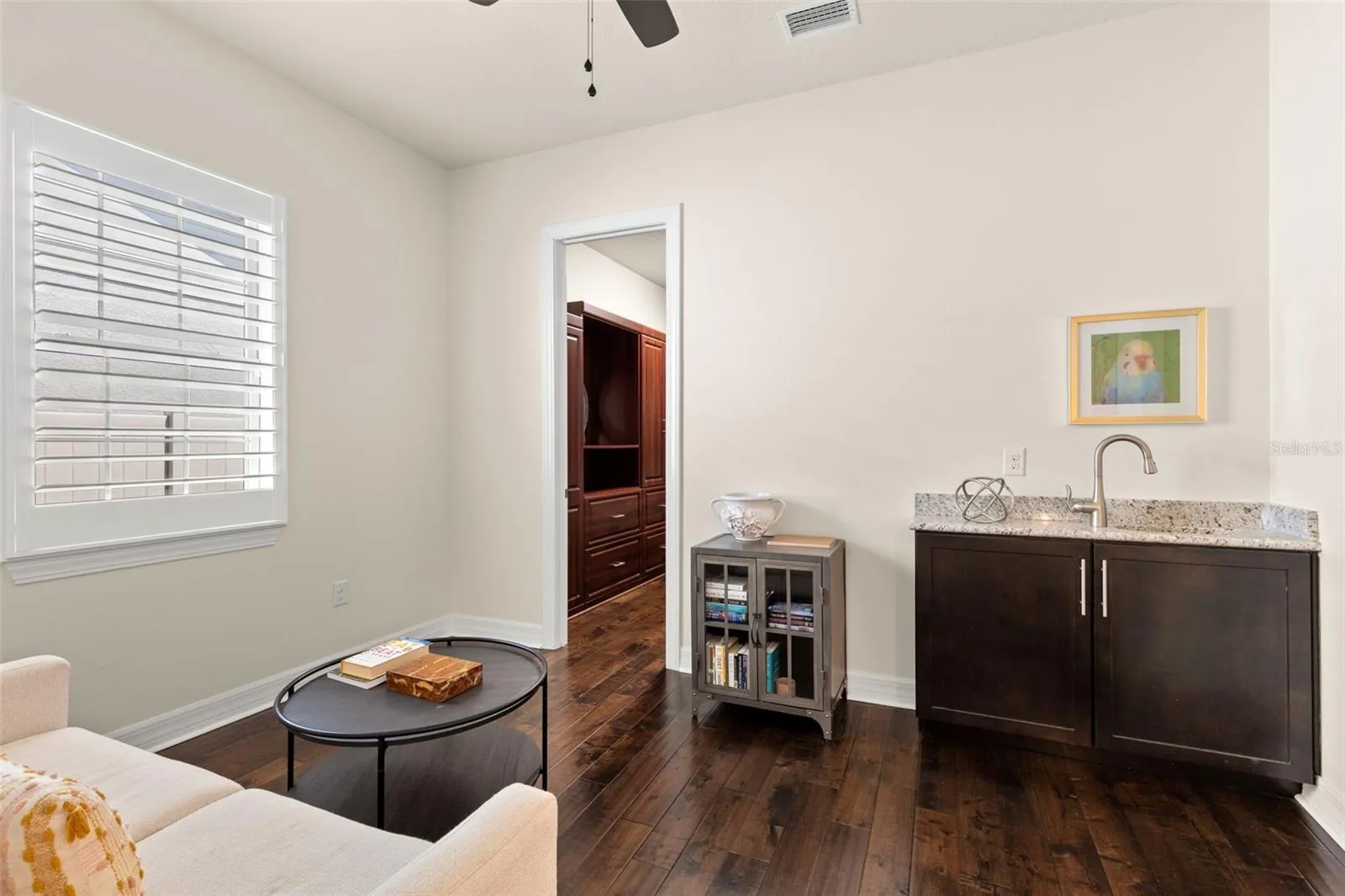 A closer look at the primary sitting area reveals its dedicated wet bar with granite counter, sink and cabinetry — perfect for morning coffee or an evening drink. Just beyond, one of the suite’s two walk-in closets adds impressive built-in storage.