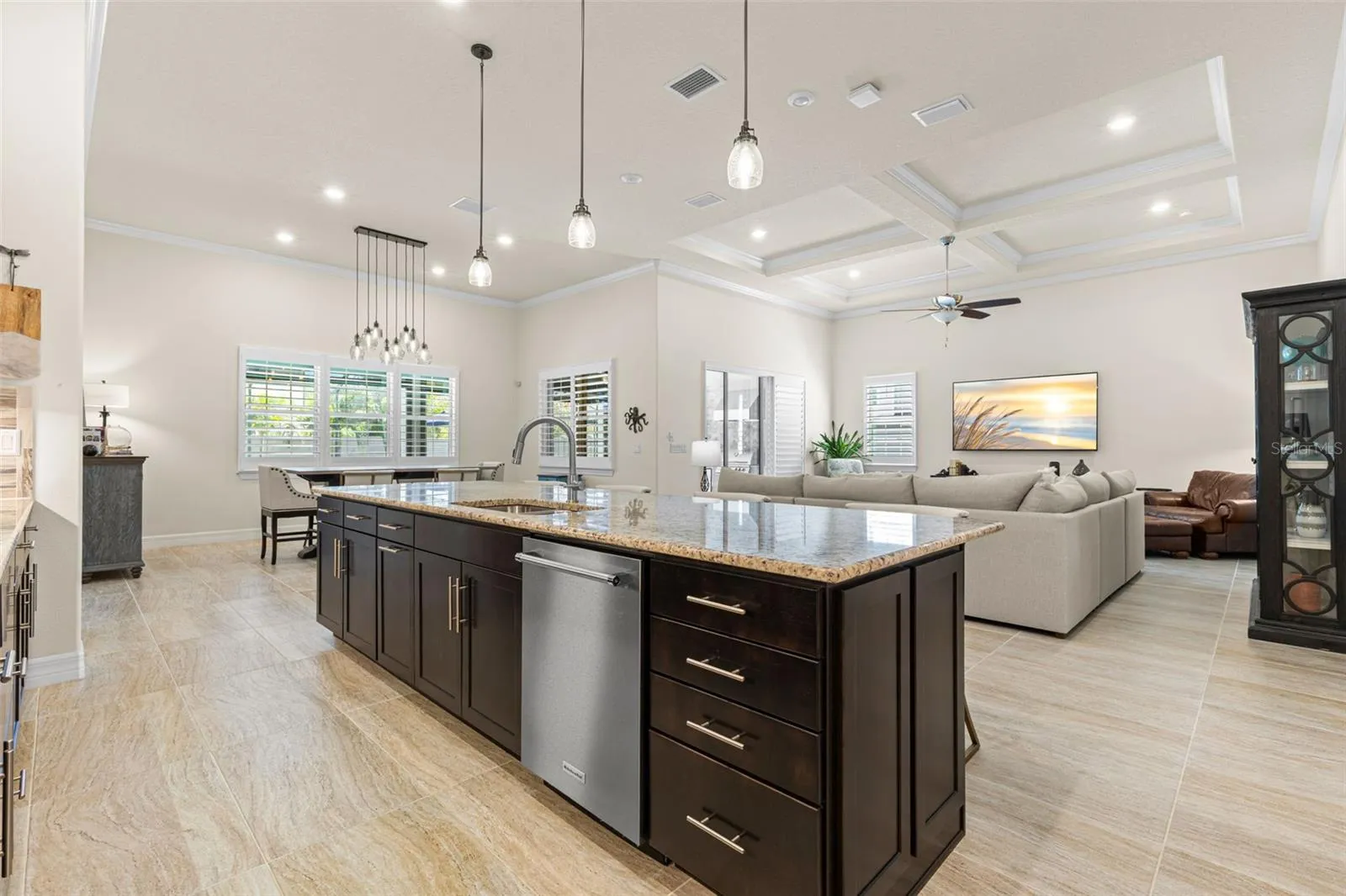 The oversized island earns its place at the center of the home, combining generous prep space, a double sink, dishwasher, deep drawers, additional cabinetry, and casual seating. From here, the kitchen opens effortlessly to both the dining area and great room, creating one expansive space for cooking, gathering, and entertaining.