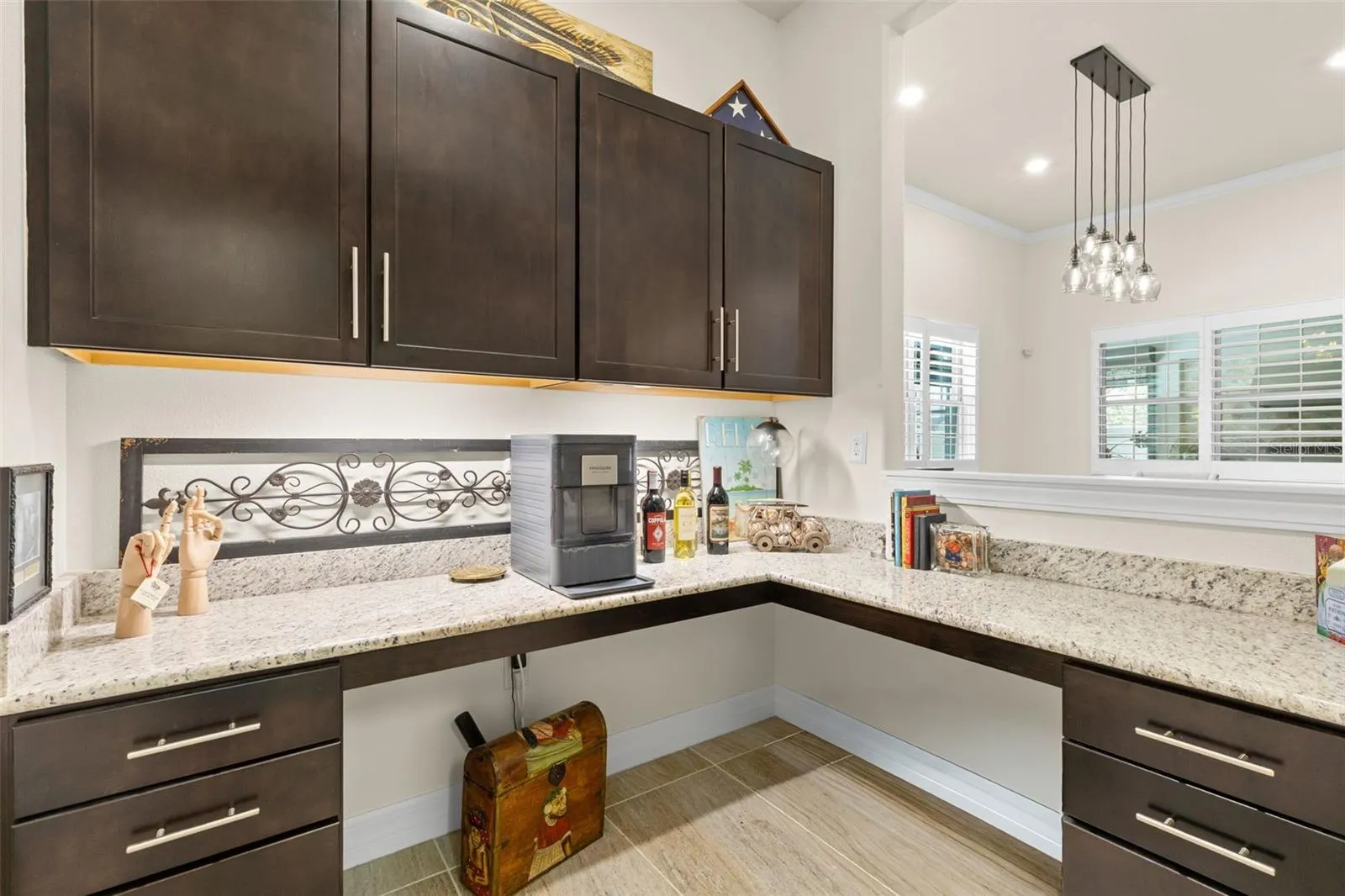 Just off the kitchen, a beautifully finished butler’s pantry-style workspace adds another layer of function, with granite counters, abundant cabinetry and a pass-through to the dining area. Use it as a coffee or wine bar, serving station, home office — or a little of each.