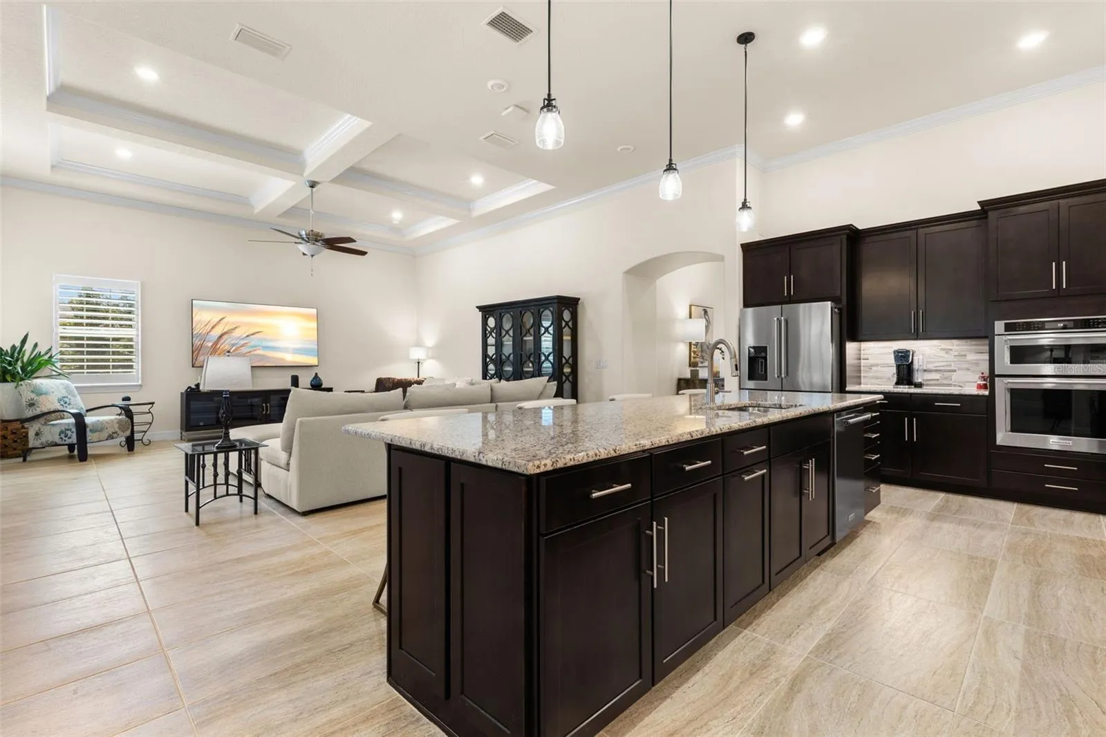 At the heart of the home, the kitchen’s oversized island brings everyone together, with generous workspace, abundant storage, and an easy connection to the great room beyond. Rich cabinetry and granite counters add warmth and contrast, while the soaring ceiling details carry seamlessly through the open living space.