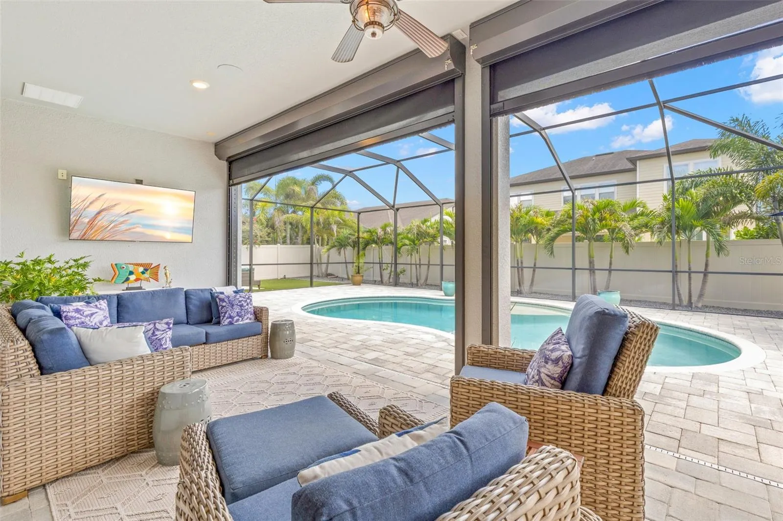 This is Florida living done right: a spacious covered lounge area overlooks the pool, with a ceiling fan and wall-mounted TV creating an easy spot to relax in the shade. A Kevlar hurricane protection system adds an important layer of protection to the lanai when needed.