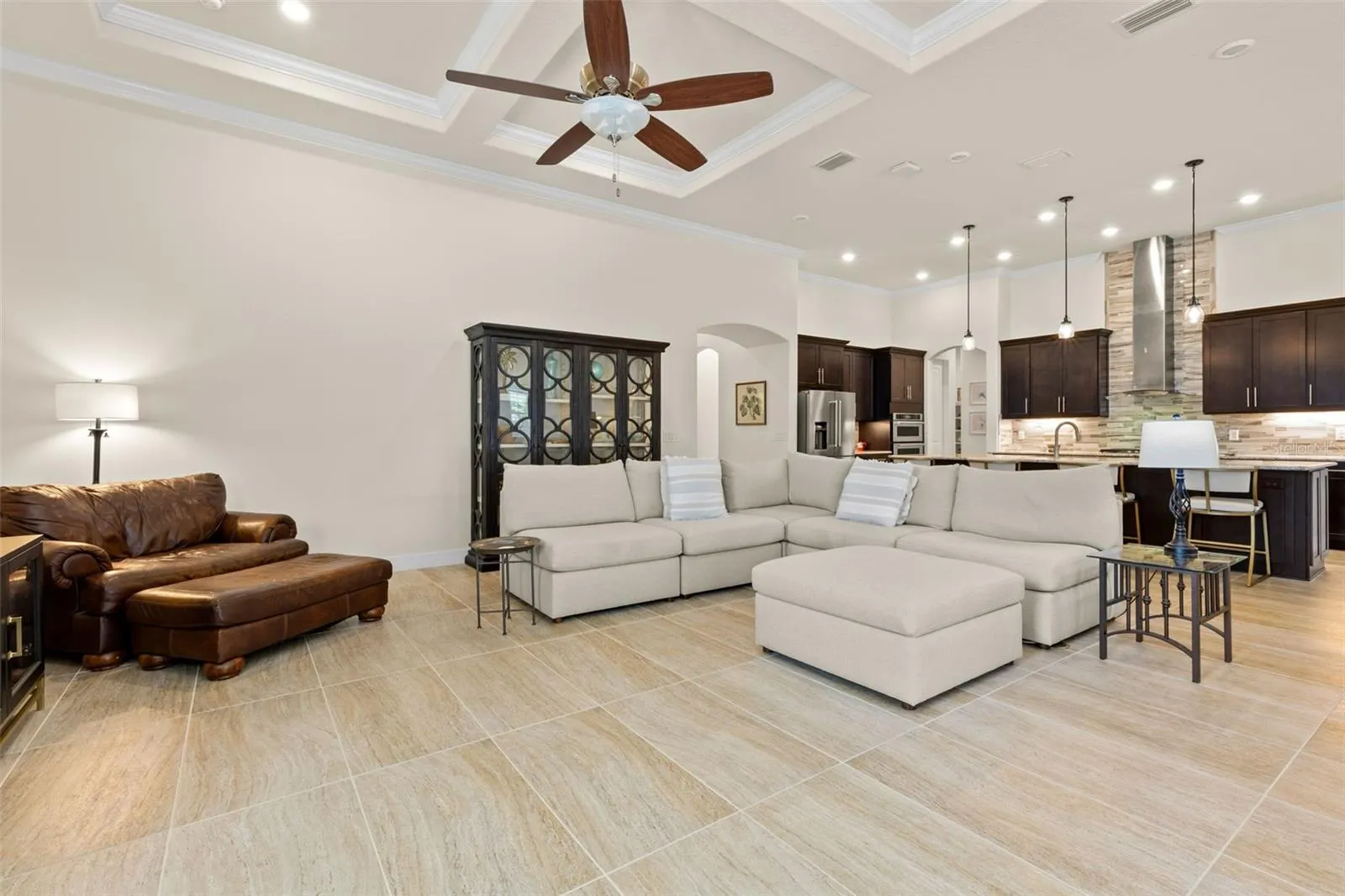 The spacious great room is made for gathering, with soaring tray ceilings, crown molding, oversized tile and plenty of room to create multiple conversation areas, while the open kitchen remains effortlessly connected to the heart of the home.