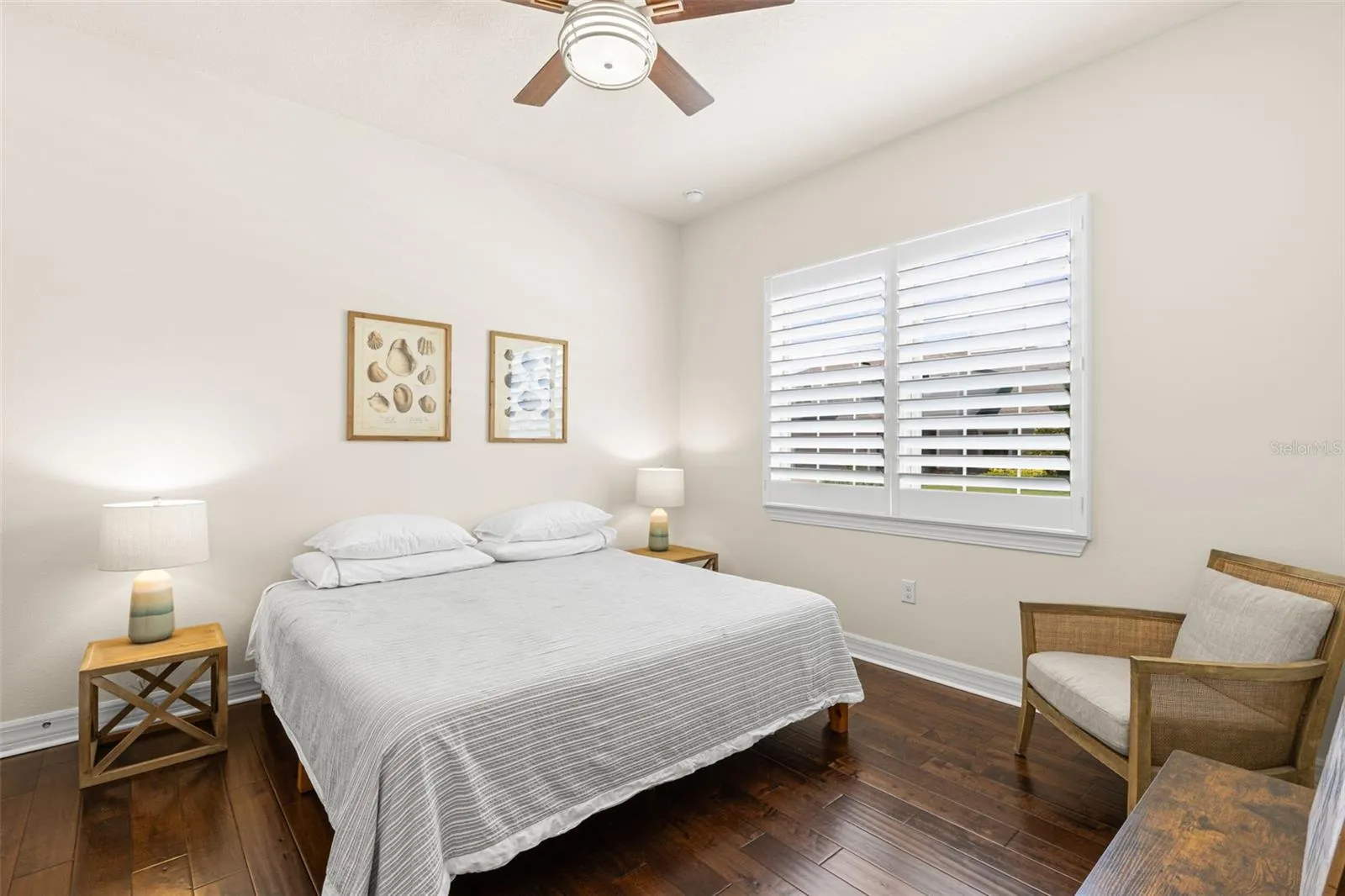 Bedroom 3 continues the home’s polished, neutral aesthetic with rich engineered hardwood flooring, plantation shutters, a ceiling fan and generous proportions that easily accommodate a full bedroom suite. Its dedicated vanity connects directly to the shared Jack-and-Jill bath just beyond.