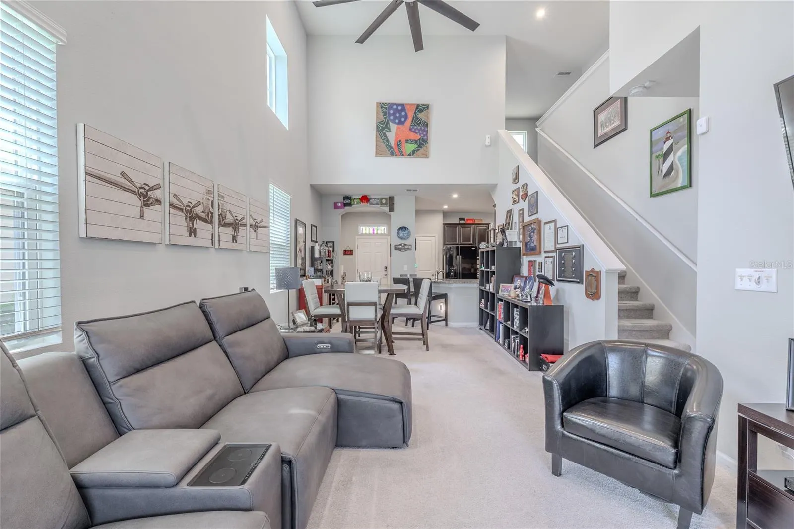 Dramatic ceiling height and clerestory windows give the main living area impressive volume, while the open layout connects the living room, dining space and kitchen with the staircase rising along one side.