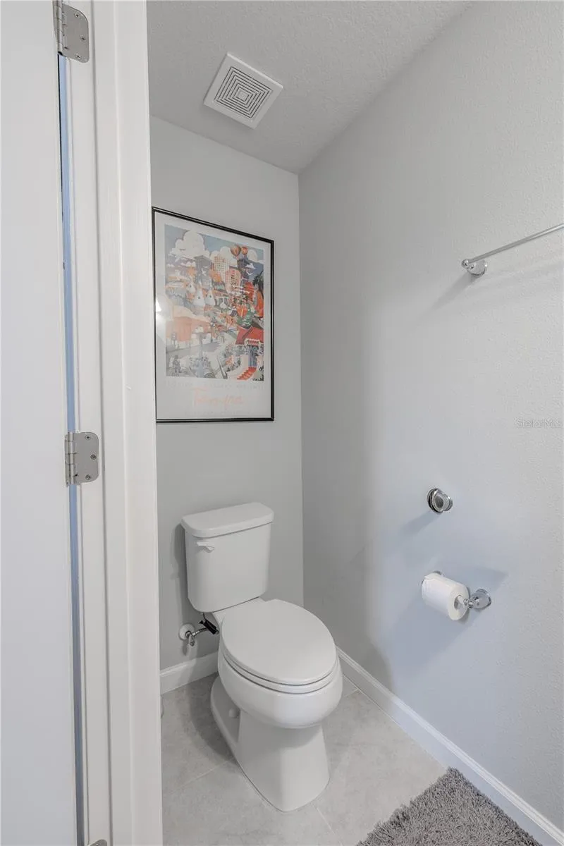 The main-level powder room continues the home’s neutral palette with tile flooring and a simple, clean layout for guests.