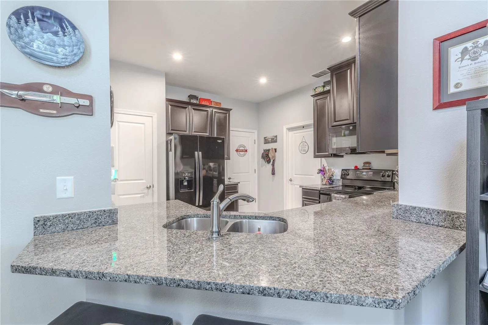 A granite-topped peninsula with a double-basin sink and breakfast-bar seating adds generous workspace while keeping the kitchen open to the adjoining living and dining area.