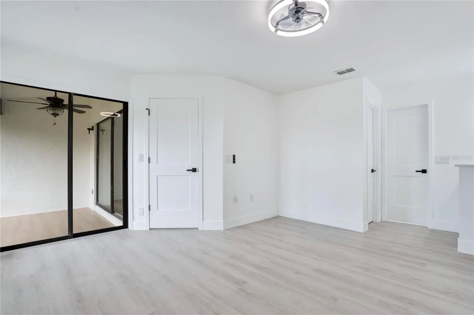 Spacious primary bedroom featuring brand-new flooring, ceiling fan and fresh modern finishes.
