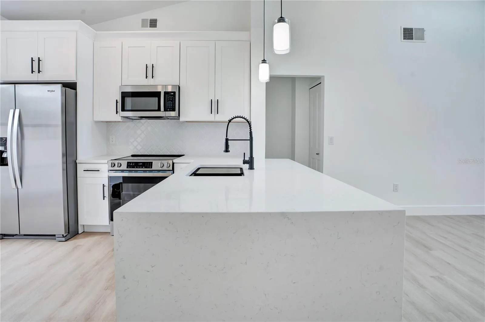 Stunning quartz waterfall-edge countertop creates a beautiful focal point in the redesigned kitchen.