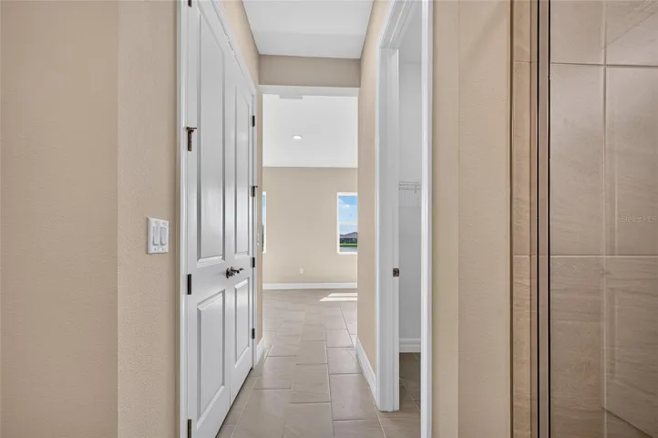 Hallway between primary bedroom into primary bath past duel closets