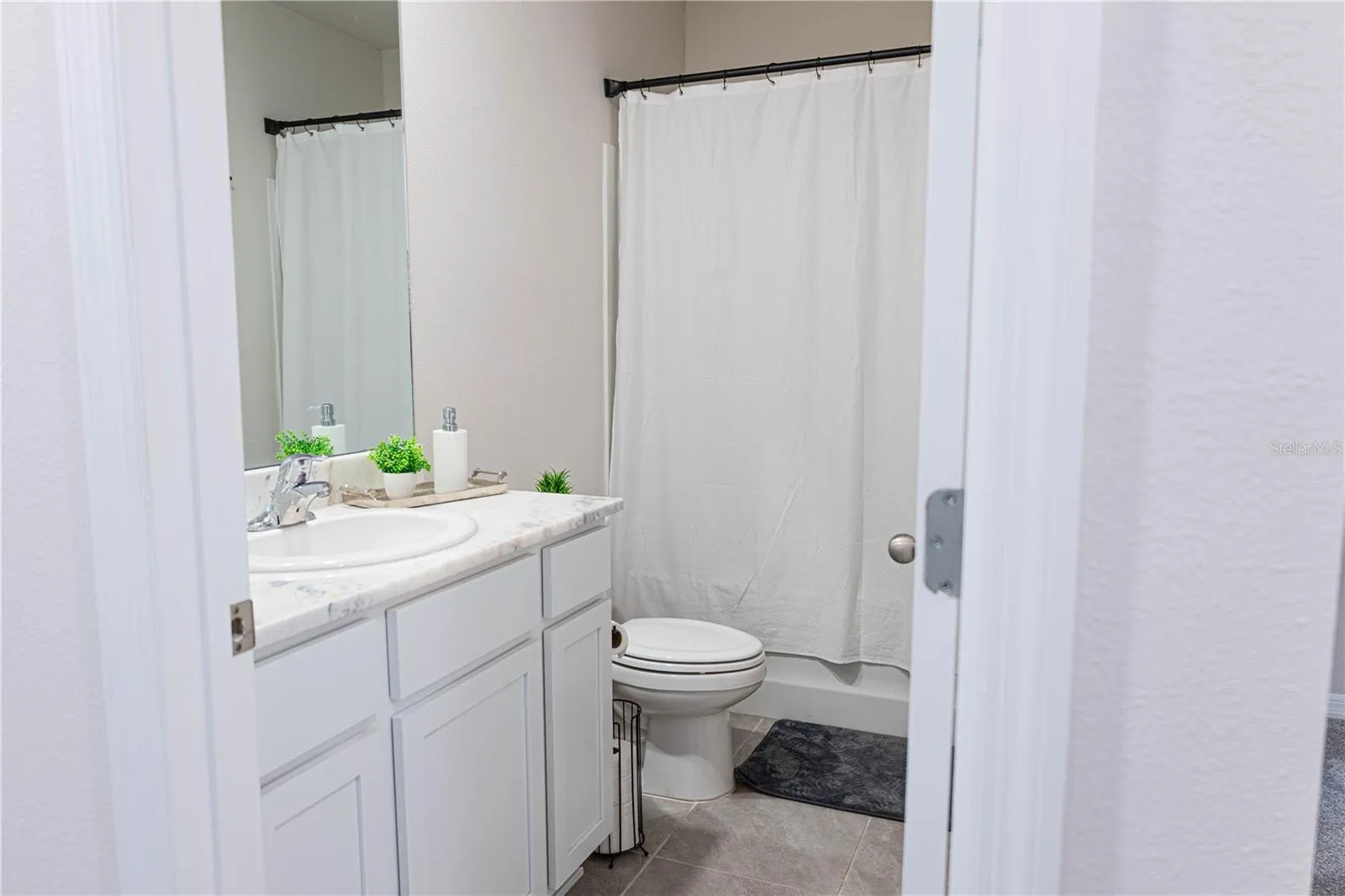 Primary en-suite bath with dual sinks, quartz countertops, and a walk-in shower — a private retreat off the main bedroom