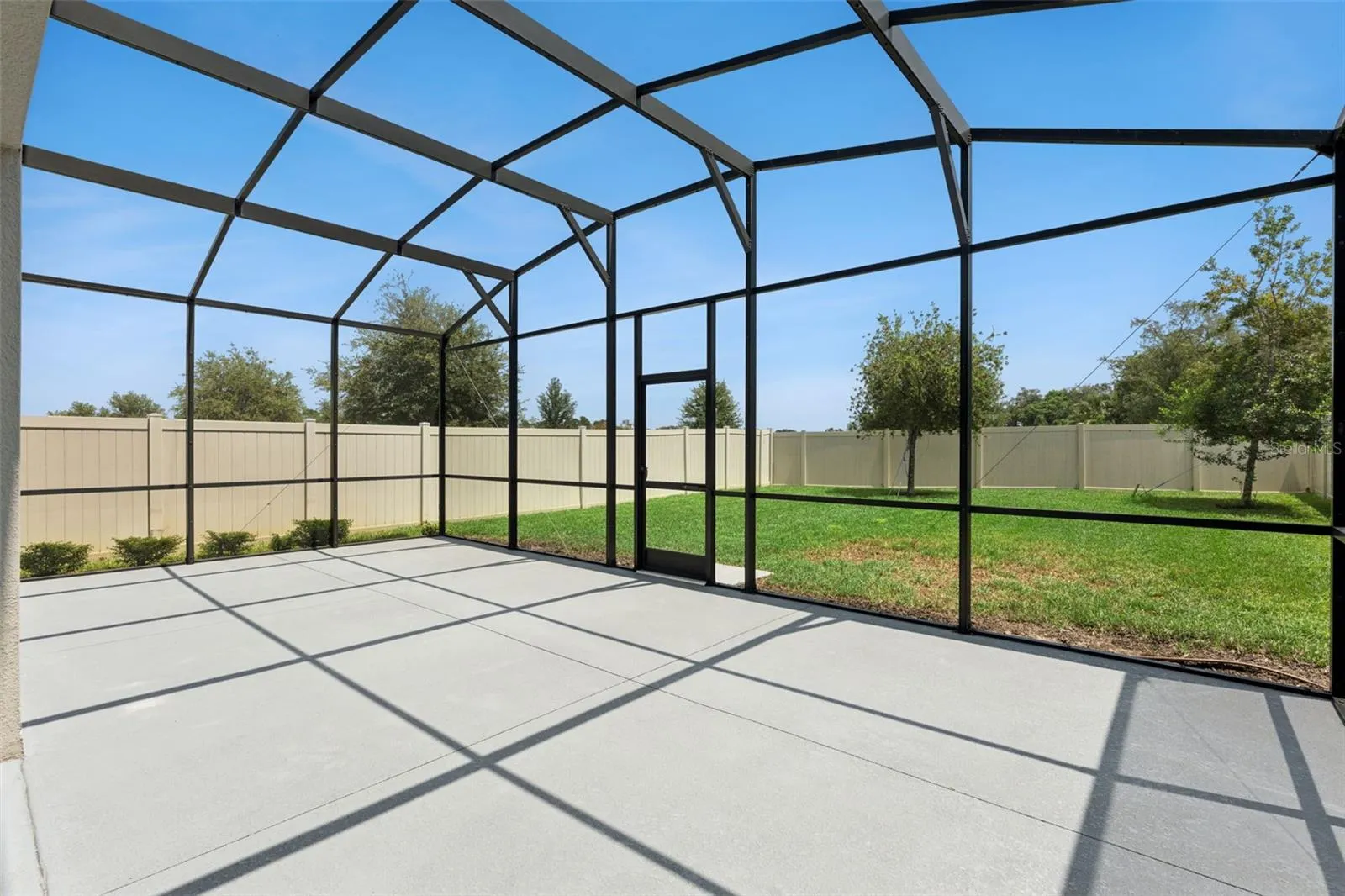 Screened Patio – Another view of the screened patio showcases its open layout and convenient access to the grassy backyard.