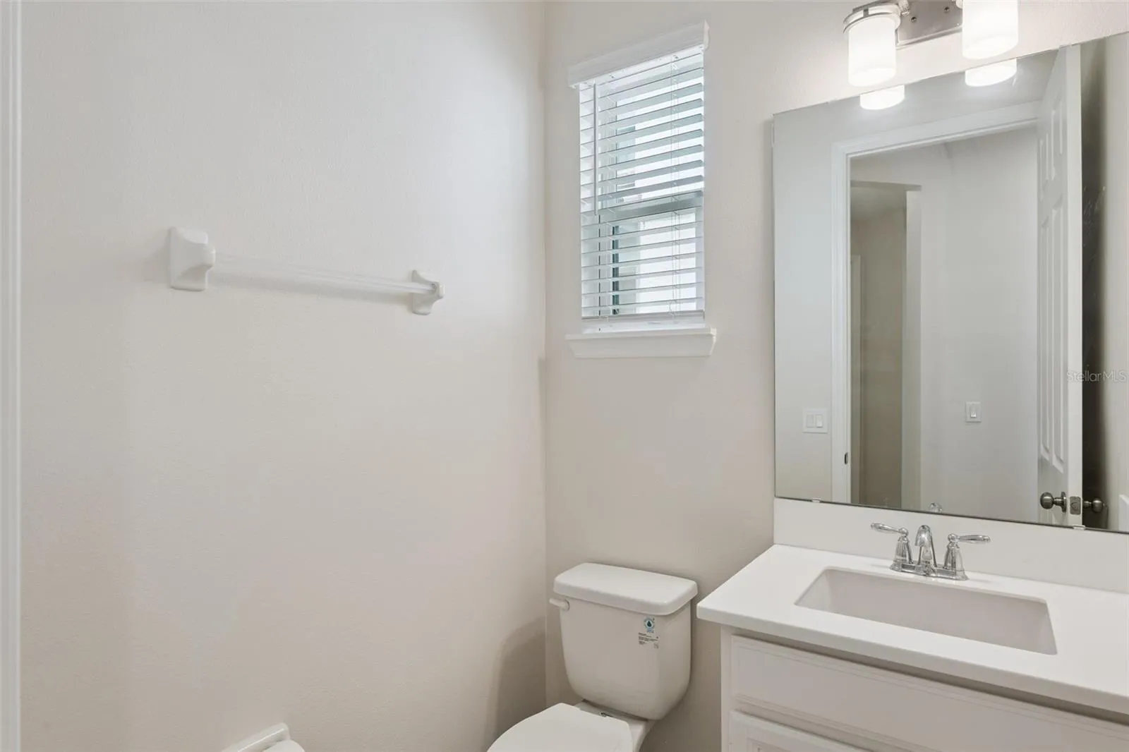 Downstairs Common Area Bathroom – Convenient main-level half bath features a crisp white vanity, large mirror, contemporary lighting, and a window that brings natural light into the space.