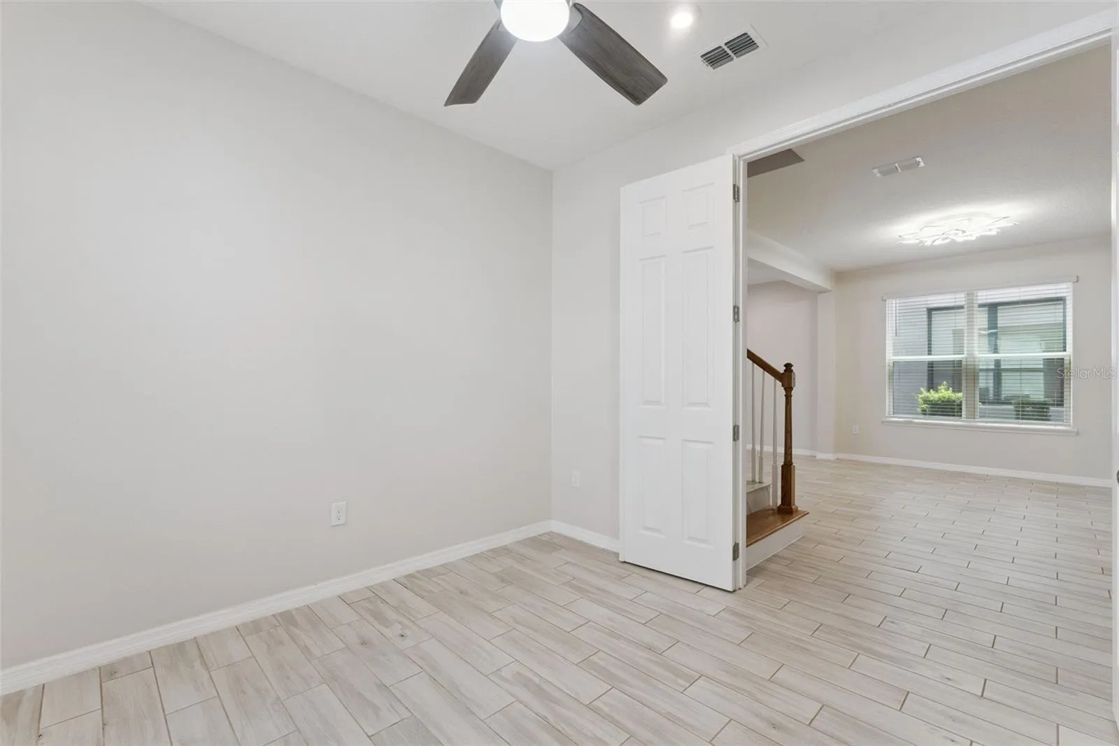 Downstairs Study – Bright, versatile main-level study with neutral finishes, tile flooring, a ceiling fan, and natural light, offering flexible space for a home office, reading room, or creative workspace.