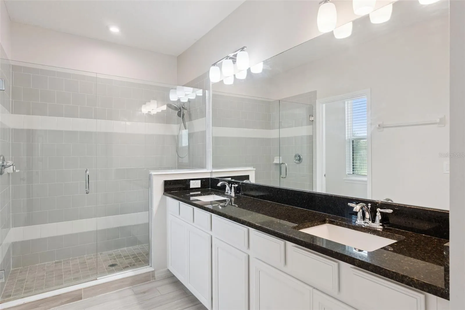 2nd Primary Bathroom – Primary bath showcases a large glass-enclosed tiled shower alongside the dual-sink vanity, creating a bright and functional ensuite retreat.