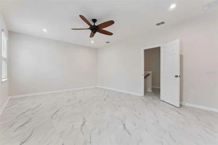 Bonus Room – Spacious enclosed upstairs bonus room with marble-look tile flooring, recessed lighting, and a ceiling fan, offering flexible space for a media room, game room, or home office.