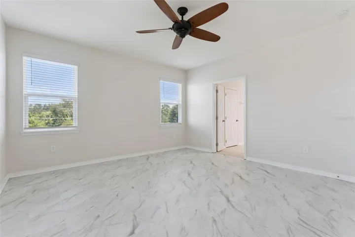 2nd Primary Suite (Upstairs) – Alternate view highlights the generous room dimensions, bright neutral finishes, and multiple windows overlooking the surrounding greenery.